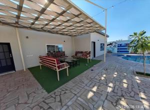 een terras met stoelen en een tafel en een zwembad bij شالية نخلة in Buraydah