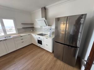 a kitchen with a stainless steel refrigerator and white cabinets at Villa Marée La Costa in La Costa