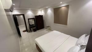 a bedroom with a white bed and a mirror at شقق درةراشد للشقق المخدومة in Hafr Al-Batin