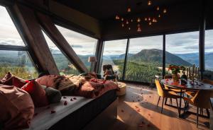 a woman in a bed in a room with huge windows at Eagle Nest Eco Lodge in Sel