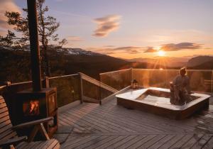 a person sitting in a tub on a deck with a fireplace at Eagle Nest Eco Lodge in Sel +6 photos