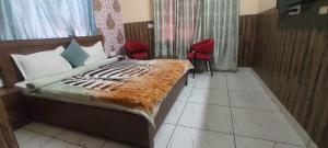 a bedroom with a bed and two red chairs at Hotel Neel Kamal Near Chandigarh Railway Station in Chandīgarh