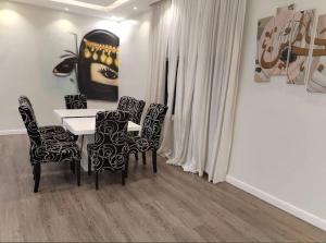 a dining room with a table and chairs and a painting at شالية نخلة in Buraydah