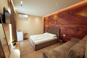 a bedroom with a bed and a painting on the wall at Central Rooms in Shkodër