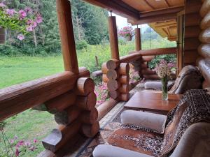 a porch of a log cabin with a table and flowers at Stream House in Lopushnoye