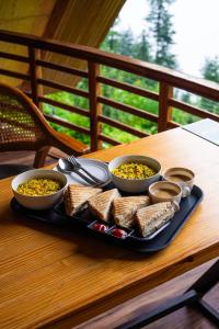 a tray of food with toast and bowls of soup at Sunrise Farm Stays in Jibhi