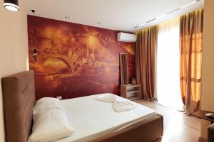 a bedroom with a bed with a painting on the wall at Central Rooms in Shkodër