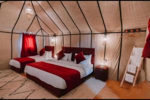 een slaapkamer met 2 bedden in een tent bij Chegaga Infinite Dunes Luxury Desert Camp in Mhamid