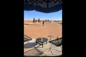 een groep mensen die kamelen berijden in de woestijn bij Chegaga Infinite Dunes Luxury Desert Camp in Mhamid