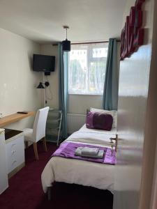 een slaapkamer met een bed, een bureau en een raam bij Love & Peace in Orpington