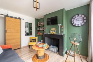a living room with a clock on a green wall at comme un air de chez soi in Calais