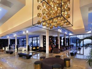 a large lobby with a chandelier and tables and chairs at Mövenpick Hotel Gammarth Tunis in Gammarth