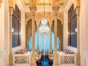 una sala da pranzo con un lampadario, tavoli e sedie di Mövenpick Hotel Al Khobar a Al Khobar