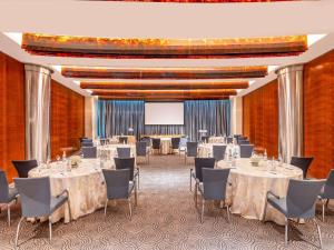 una sala conferenze con tavoli, sedie e schermo per proiezioni di Mövenpick Hotel Al Khobar a Al Khobar