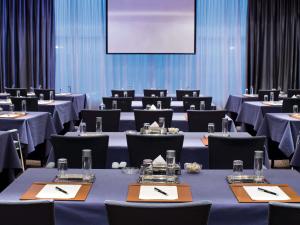 una sala conferenze con tavoli, sedie e uno schermo di Mövenpick Hotel Al Khobar a Al Khobar