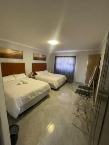 a hotel room with two beds and a desk at Eighth Avenue Self Catering Accommodation in Lüderitz