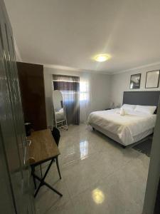 a bedroom with a bed and a table and a chair at Eighth Avenue Self Catering Accommodation in Lüderitz +1 photo