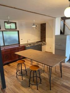 a kitchen with a wooden table and two stools at イヤシロチomoya in Onomichi