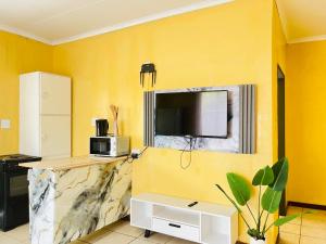 una cucina con pareti gialle e bancone con forno a microonde di Genesis Guesthouze a Bela-Bela