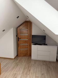 a attic room with a door and a television at Willa Rytel in Rytel