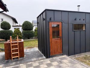 a black shed with a wooden door and a ladder at Willa Rytel in Rytel