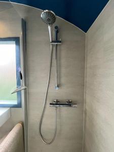 a shower with a shower head in a bathroom at Tuiny House Noordwijk in Noordwijk