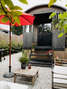 a patio with a table and a red umbrella at Tuiny House Noordwijk in Noordwijk