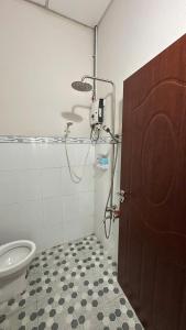 a bathroom with a shower and a toilet and a door at Khách sạn Nhất Phương 2 in Ấp Ðông An (1)