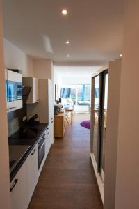 a kitchen with white cabinets and a living room at Business Apartments Höfle in Heppenheim an der Bergstrasse