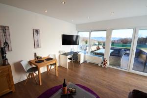 a living room with a table and a tv on a wall at Business Apartments Höfle in Heppenheim an der Bergstrasse
