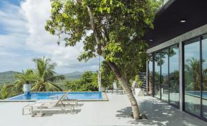 ein Pool mit einem Baum neben einem Gebäude in der Unterkunft Eskobar Villa Exclusive in Baan Tai
