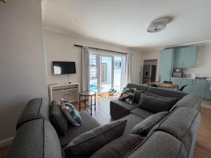 ein Wohnzimmer mit Couch und Fernseher und eine Küche in der Unterkunft Ocean Whisper in Plettenberg Bay