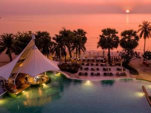 a view of a pool with tables and chairs at Mövenpick Siam Hotel Na Jomtien Pattaya in Na Jomtien