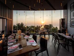 a restaurant with tables and chairs with the sunset in the background at Mövenpick Siam Hotel Na Jomtien Pattaya in Na Jomtien