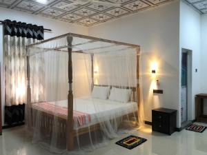 a bedroom with a canopy bed with white curtains at Calm Garden Cabanas in Tangalle