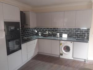 a white kitchen with a washing machine in it at Double room beside tramline in Dublin