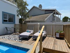 eine Holzterrasse mit zwei Betten und einem Swimmingpool in der Unterkunft Ocean Whisper in Plettenberg Bay