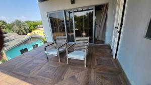 a patio with two chairs and a table on a balcony at Beach House at Kokrobite in Kokrobite