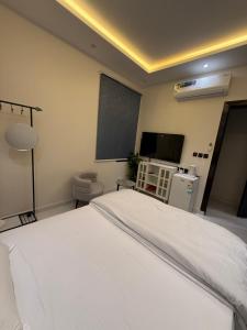 Schlafzimmer mit einem weißen Bett und einem Flachbild-TV in der Unterkunft استديو المعتليه in Riad