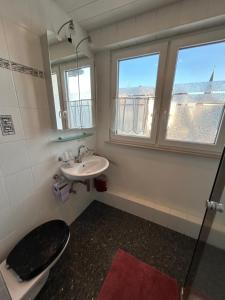 a bathroom with a toilet and a sink and a window at Apartment am Rathaus 3SZ in Rödermark