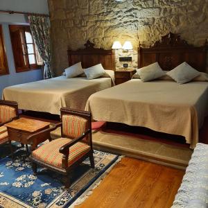 een slaapkamer met twee bedden en stoelen en een stenen muur bij Hotel Castillo el Collado in Laguardia