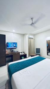 ein Hotelzimmer mit einem großen Bett und einem Flachbildfernseher in der Unterkunft Kaloor Residency in Ernakulam