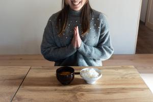 a woman sitting at a table with a bowl of rice at Guest House KITOEDA in Nikko
