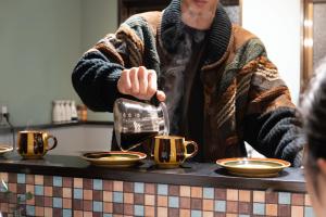 a woman is pouring coffee into cups on a counter at Guest House KITOEDA in Nikko