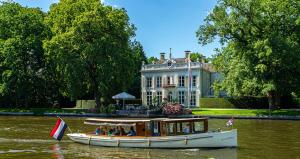 een boot in het water voor een huis bij Logement aan de Vecht in Breukelen