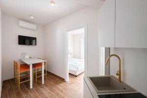 eine Küche mit einem Waschbecken und einem Tisch sowie ein Schlafzimmer in der Unterkunft Maison Hermes in Mailand