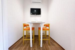 einen Tisch mit vier Stühlen und einen TV an der Wand in der Unterkunft Maison Hermes in Mailand