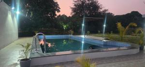 a swimming pool with a person in the water at night at Amrutvel Resort in Pune +8 photos