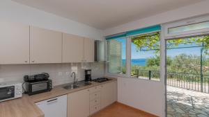 een keuken met witte kasten en een groot raam bij Villa Radic - Makarska by Villas Guide in Baška Voda
