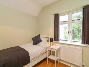 a bedroom with a bed and two windows at School House in Ivybridge